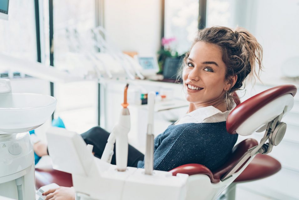 Young woman sitting on a dentist's chair Patient seated in dentist chair during an appointment with a dental hygienist in Brantford