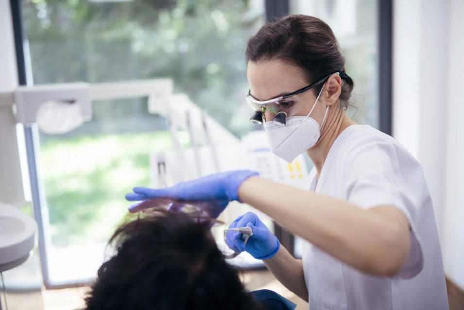 Female Dentist Working On Patient.