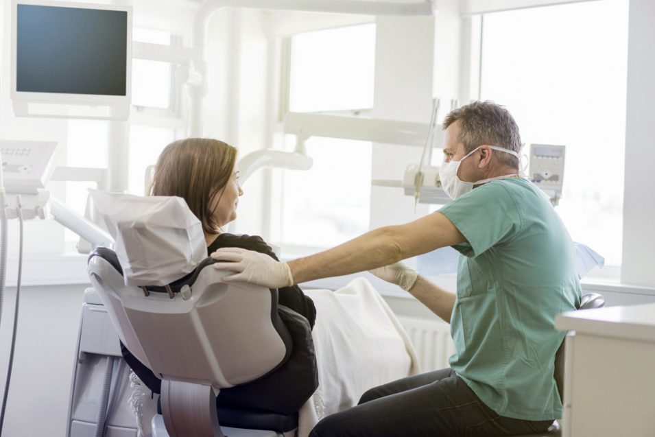 Dentist talking to female patient in clinic Dentist talking to female patient about a dental exam in Brantford