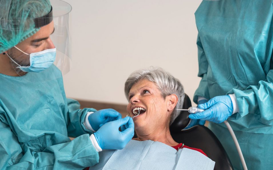 Man dentist operating senior woman in dental clinic - Oral healthcare assistance concept Oral surgeon Brantford
